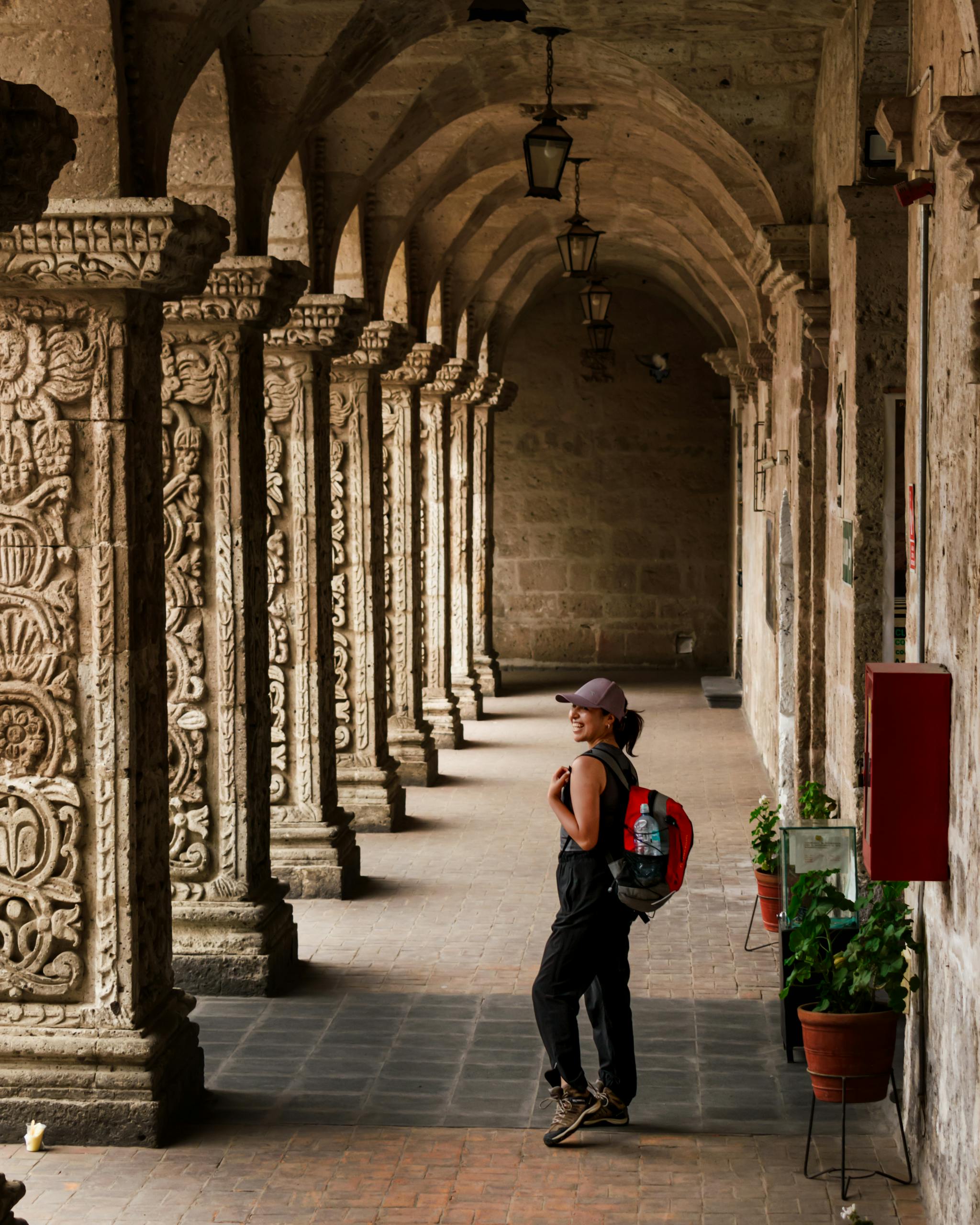 A tourist admiring the ornate stone columns of a historic cloister in Arequipa, Peru.